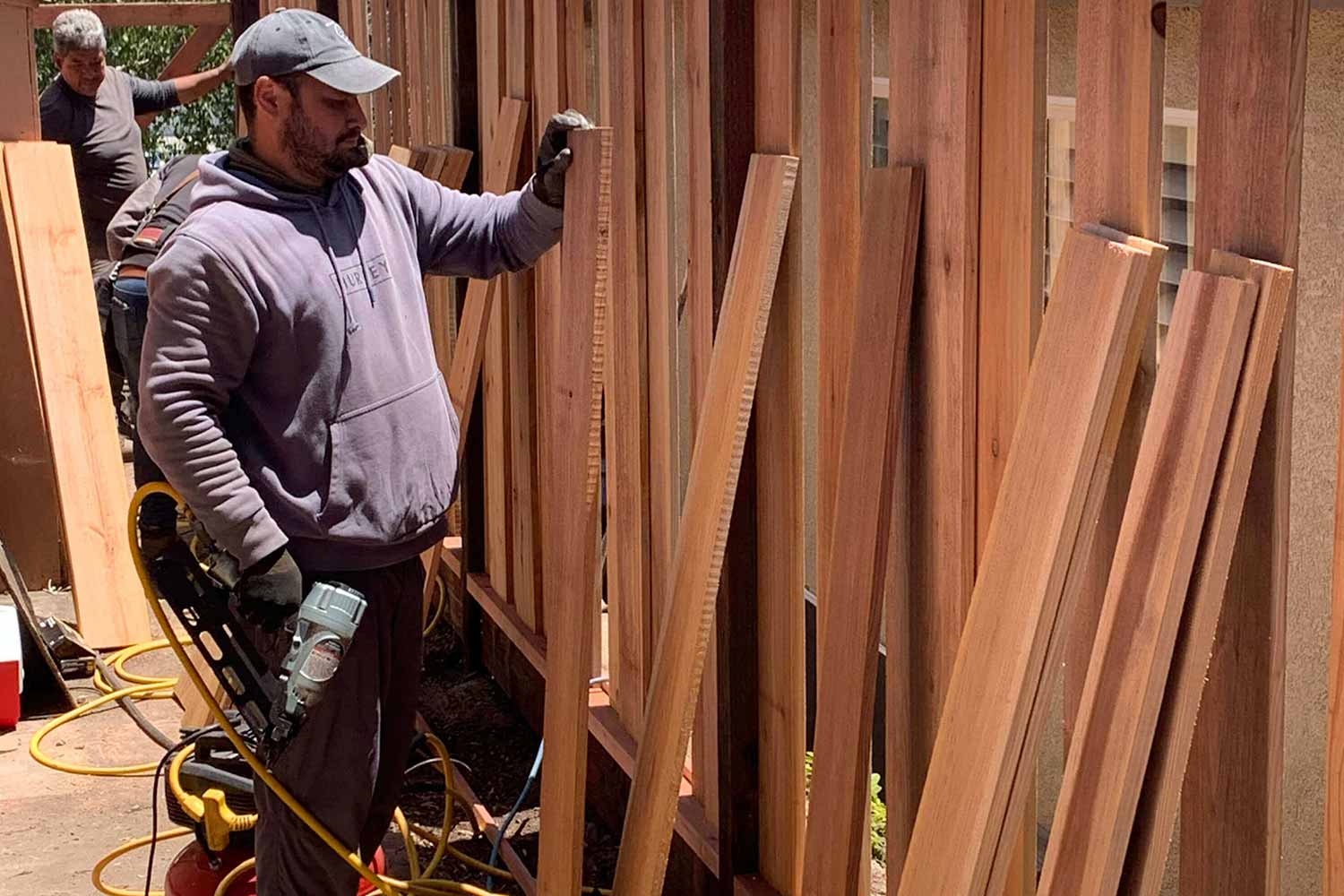 Crew installing wooden fence panels using nail gun