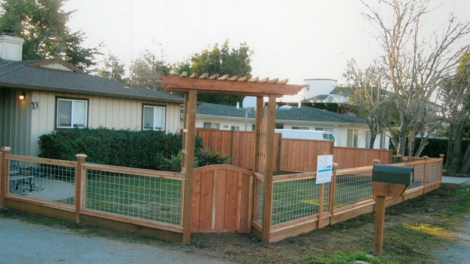 Wooden gate with trellis and wire mesh fencing