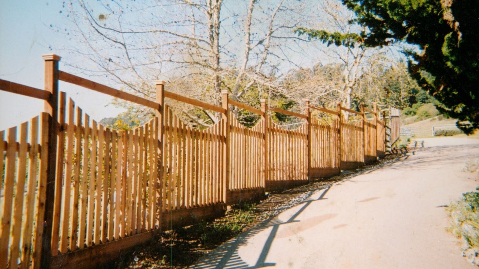 Wooden fence with decorative tops along a gravel path